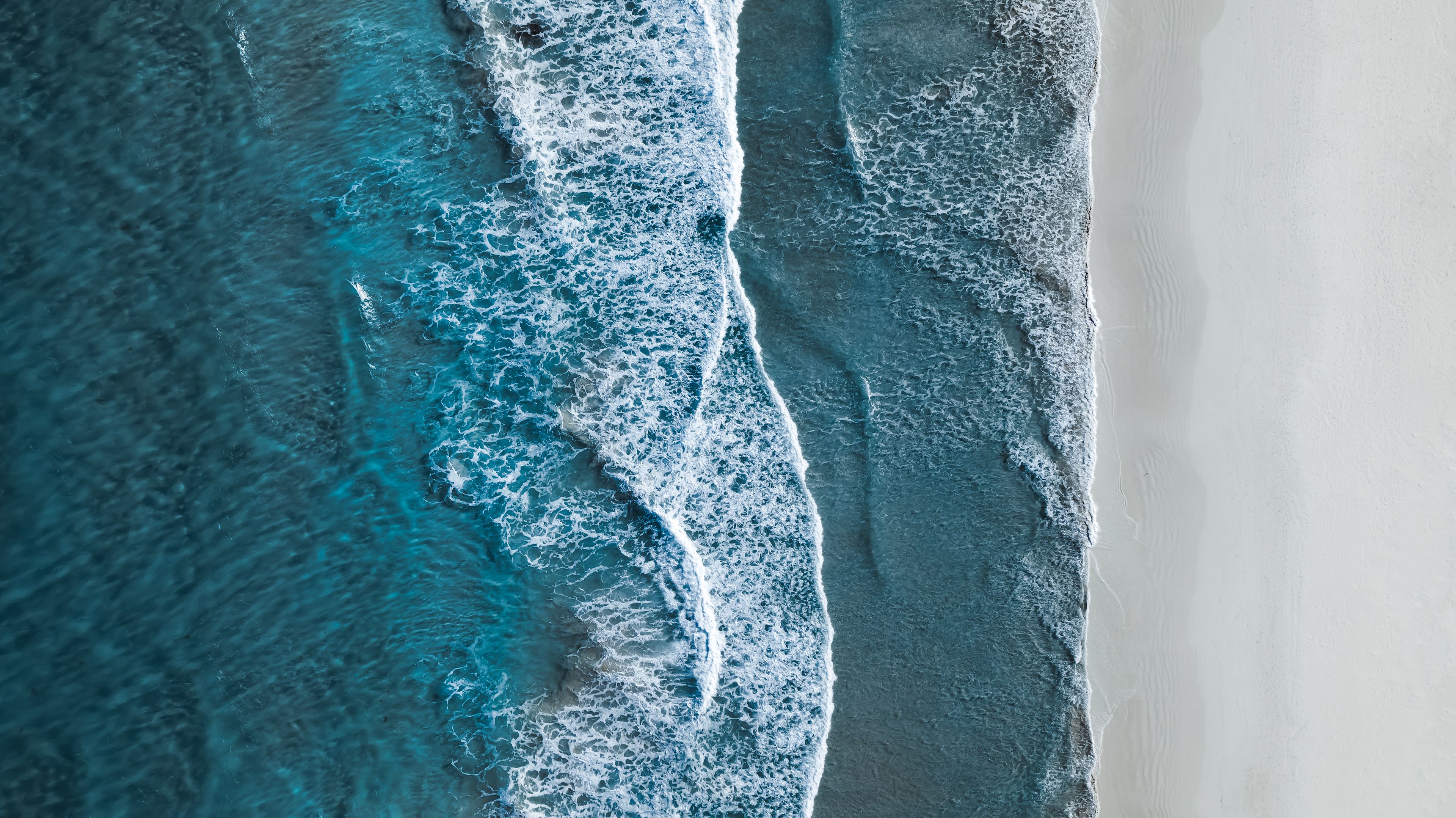 Drone shot showing waves rolling onto a beach. Location: Esperance, Australia. Photographer: Abstract Aerial Art. Source: Getty Images. Used under licence. drone shot of water rolling into water