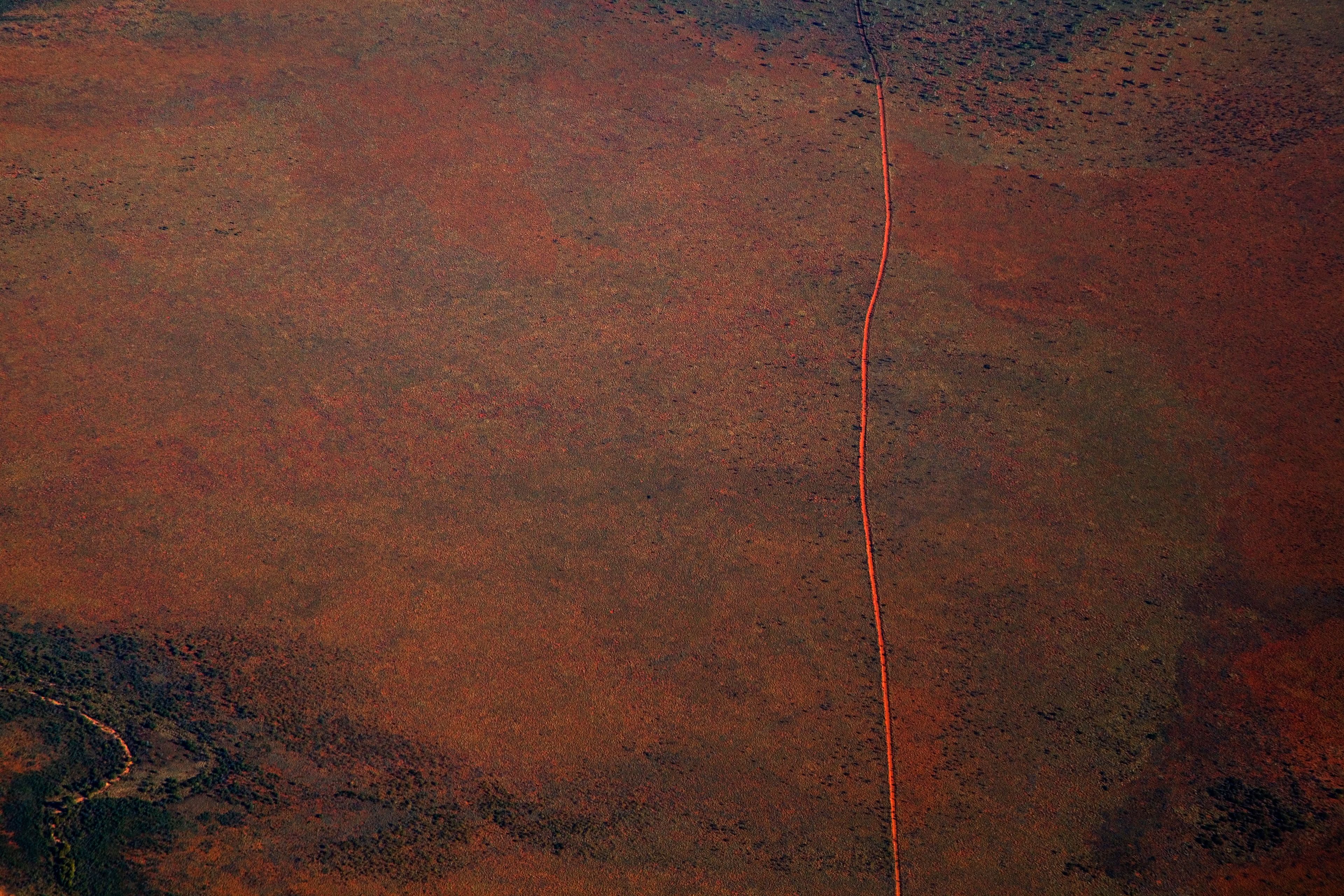 Aerial view of a dirt road positioned in a remote landscape. Photographer: Tobias Titz. Source: Getty Images. Used under licence. a red dirt track against brown red landscape