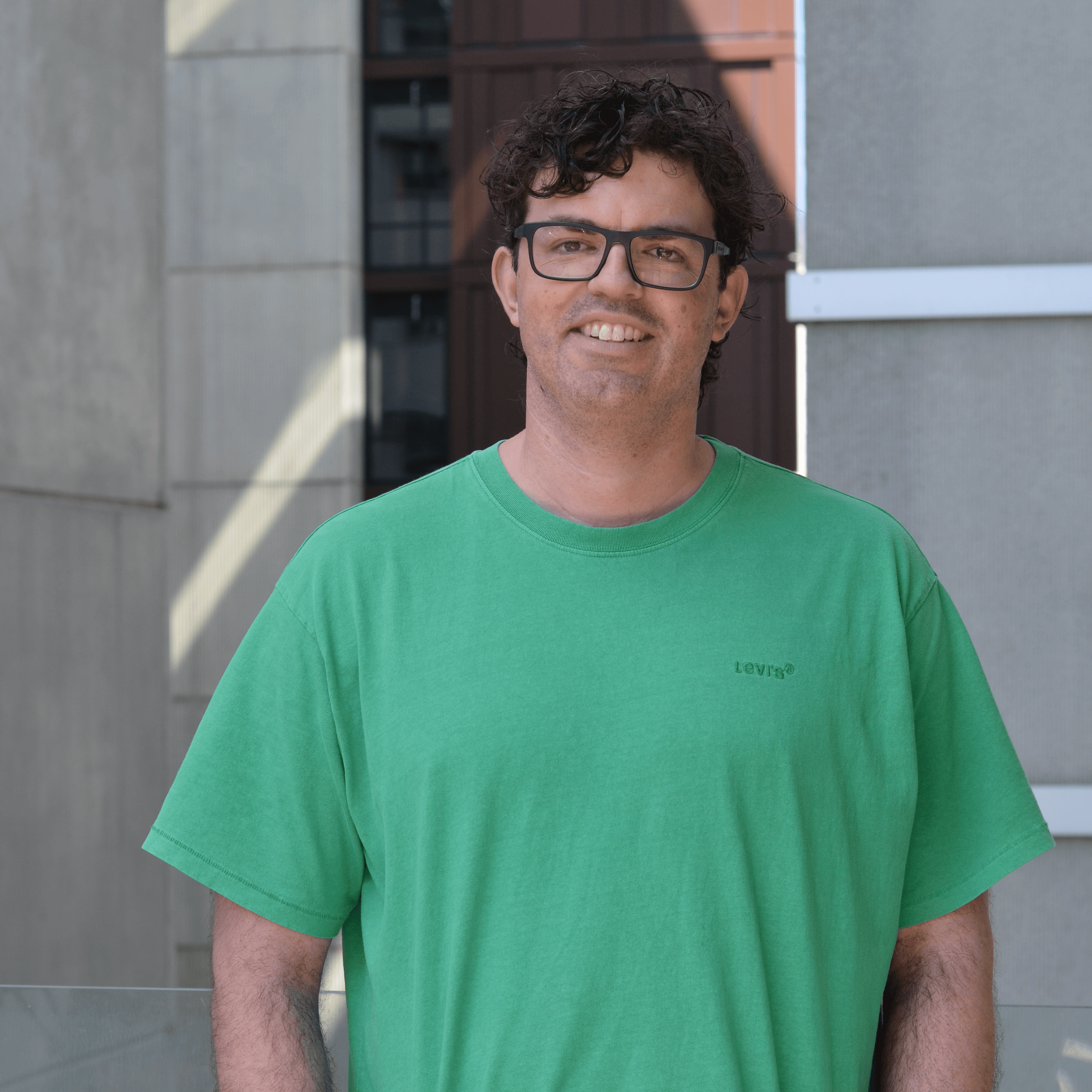 Justin Wilkey, Research Fellow Image Justin Wilkey smiles in a green tshirt outside the faculty of education at Unimelb