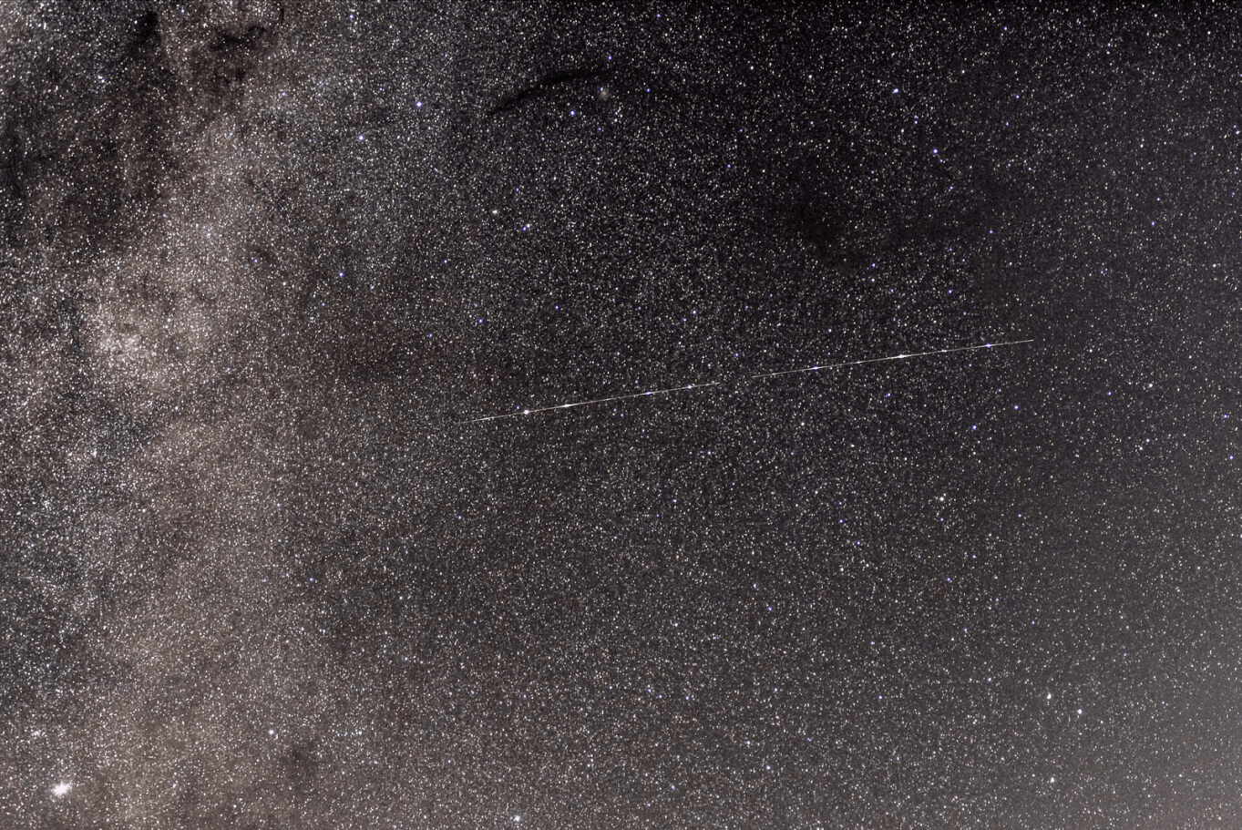 A shooting star represented by a white line against a background of millions of stars in varying shades of pink and black.