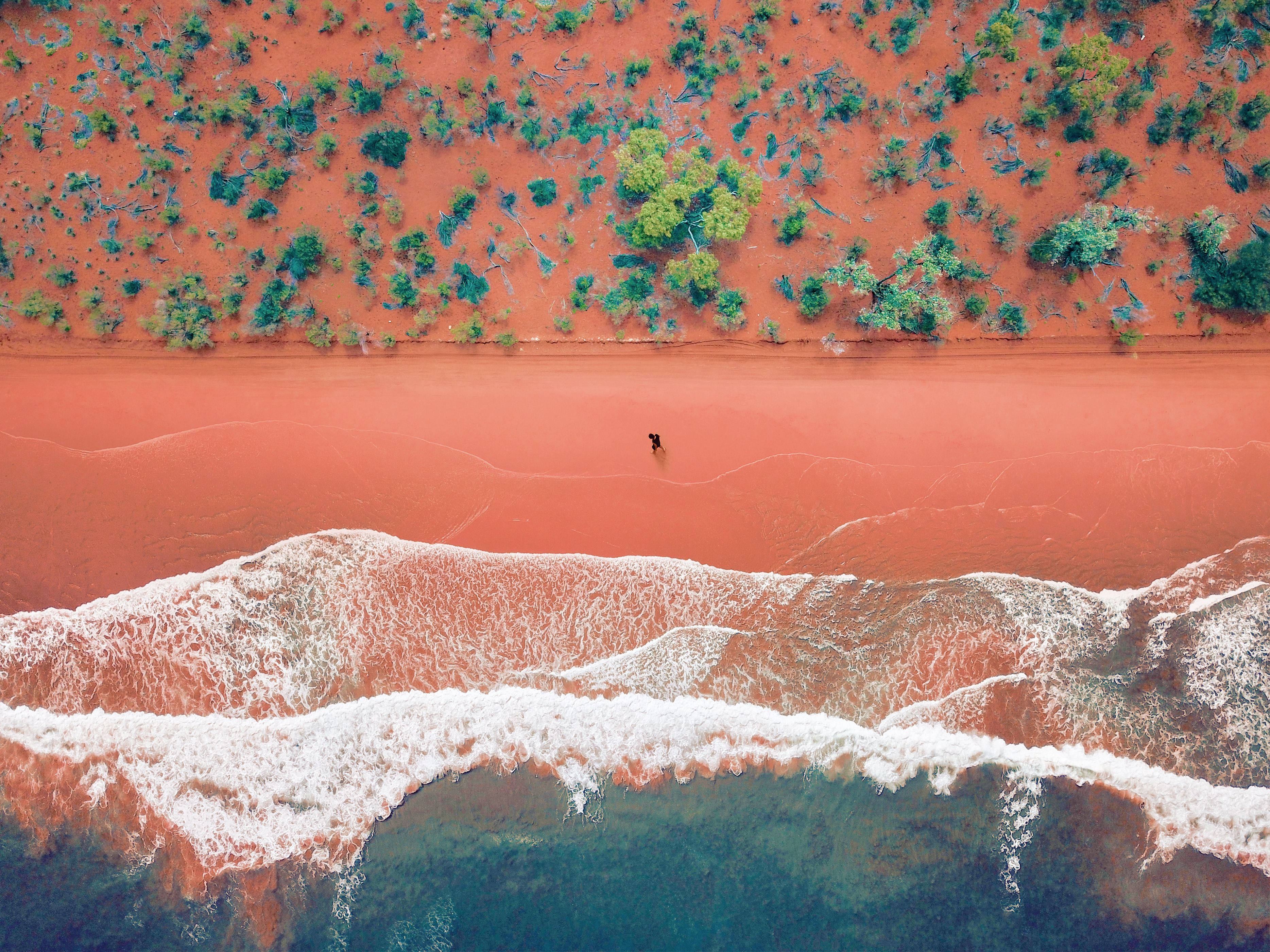 Aerial View Of A Solo Man Walking On A Bright Rusty Red Sandy Beach - Getty Images Rusty Red Sandy Beach