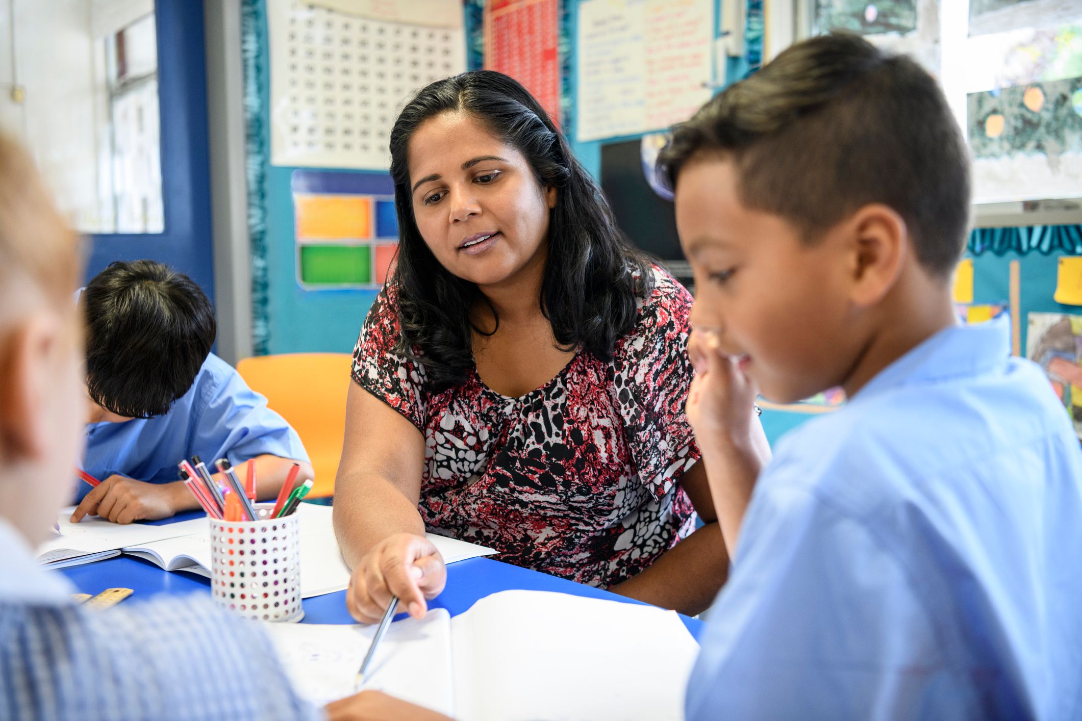 Teacher Engagement with Indigenous Knowledge IMAGE Aboriginal primary school teacher helping young boy in the classroom.
